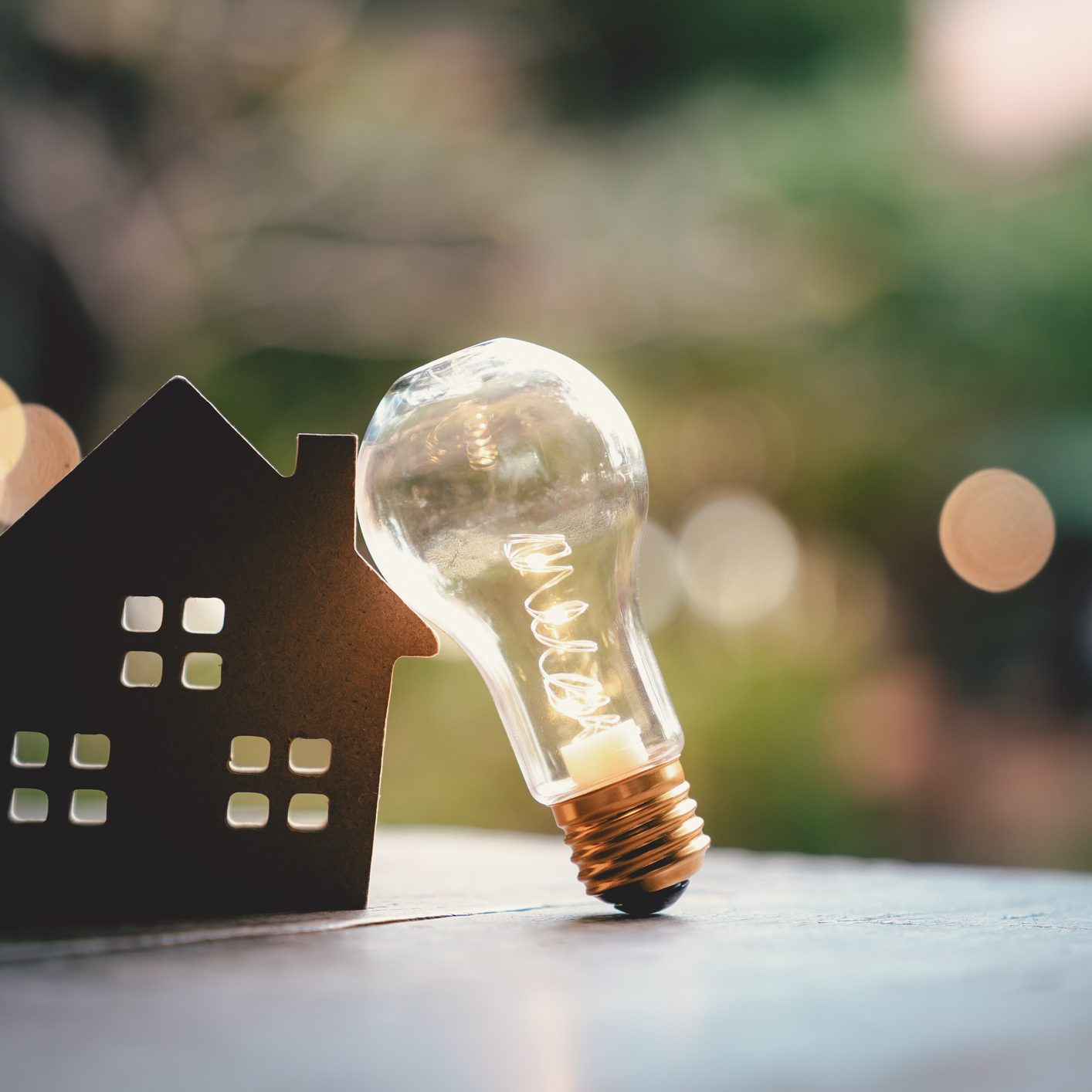 Light bulb with wood house on the table, a symbol for construction, Creative light bulb idea, power energy or business idea concept ecology, loan, mortgage, property or home.